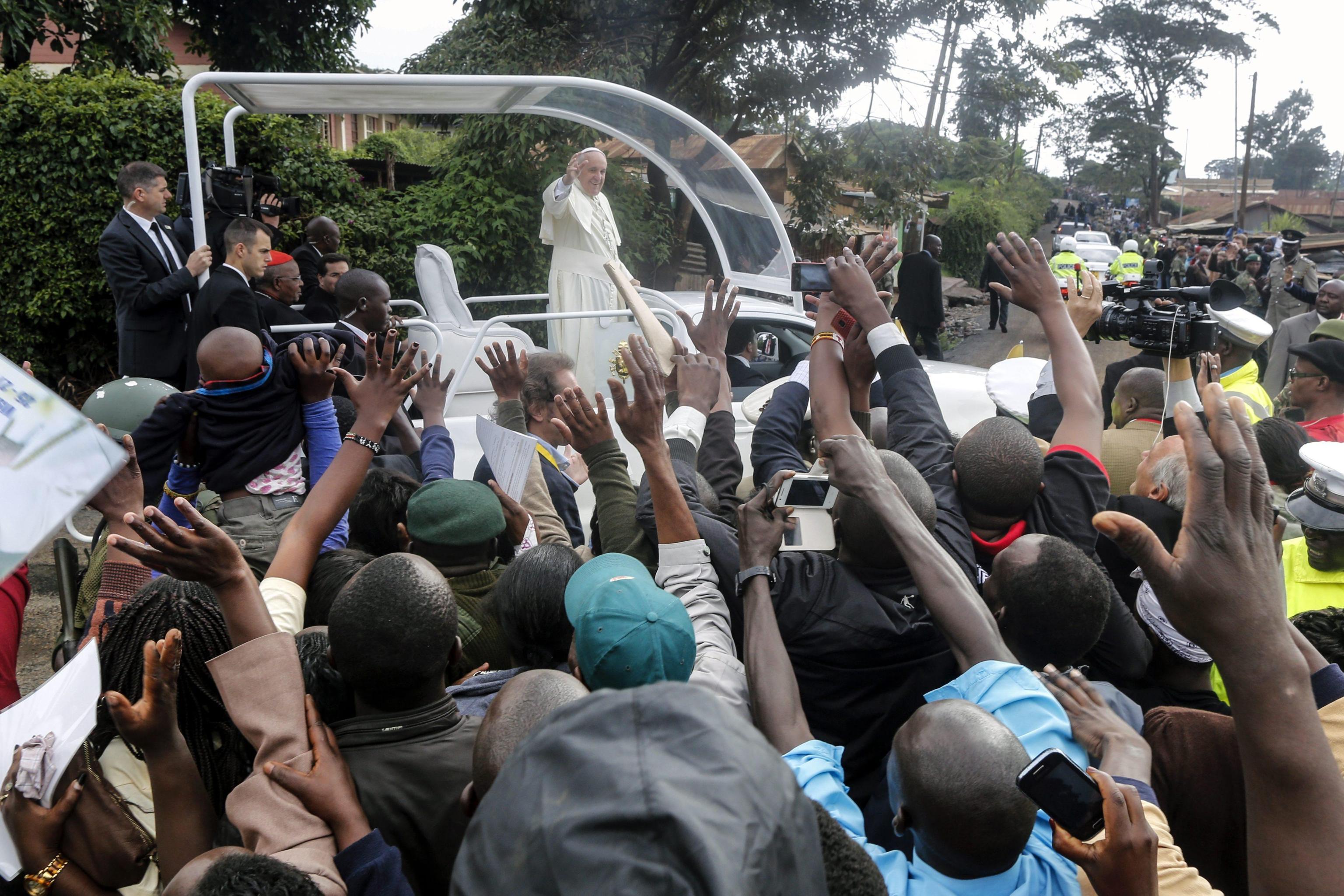 Pope Francis waves at faithfuls as he arrives with the Popemobile to attend a mass at St Joseph Catholic church in Kangemi slum in Nairobi